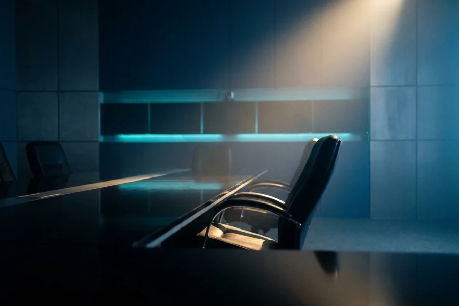 Empty corporate boardroom with one chair pulled back, symbolizing 2026 Big Tech AI layoffs at Meta and Microsoft